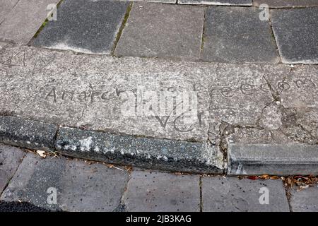 „Anarchie ist Freiheit“-Botschaft in nassem Zement auf Straßenbelag in Penarth, Südwales Stockfoto