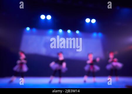 Ein verschwommener abstrakter Hintergrund eines Tanzfestivals von einer Gruppe von Mädchen in der Anzahl von vier Personen. Helle Beleuchtung der blauen Tanzfläche. Hochwertige Fotos Stockfoto