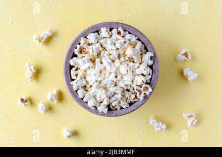 Frisches Popcorn in einer Schüssel auf gelbem Hintergrund. Draufsicht. Stockfoto