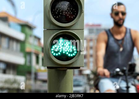 Grüne Fahrradampel mit Radfahrer im Hintergrund. Stockfoto