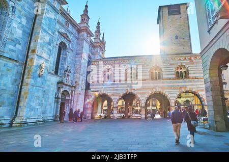 COMO, ITALIEN - 20. MÄRZ 2022: Das mittelalterliche Gebäude der Gemeinde Sitz - Broletto di Como mit hohen Turm und Arkade, an der Kathedrale, auf Stockfoto