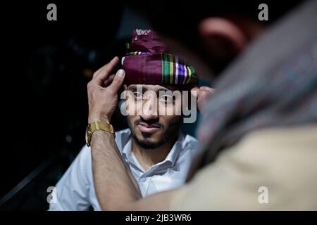 Sanaa, Jemen. 02.. Juni 2022. Ein jemenitischer Mann (R) hilft einem Bräutigam Majd Alshaibany in traditioneller Hochzeitskleidung vor seiner Hochzeitszeremonie in Sanaa. Hochzeiten im Jemen sind voller verschiedener sozialer Bräuche und Rituale, die Tausende von Jahren zurückreichen. Quelle: Hani Al-ANSI/dpa/Alamy Live News Stockfoto