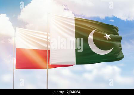 Sonniger blauer Himmel und Flaggen von pakistan und polen Stockfoto