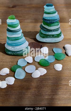 Am Meer polierte Kieselpyramiden auf einem hölzernen Hintergrund mit Muscheln Stockfoto