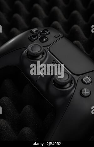 27. Mai 2022, Odessa, Ukraine. Schwarzes Gamepad Sony PlayStation 5 auf dunklem Schaumstoff-Hintergrund. Dualsense-Controller. Stockfoto