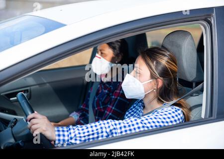 Junge hispanische Frau in medizinische Maske Auto fahren Stockfoto