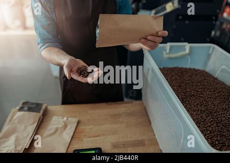 Männliche Hände halten frisch geröstete Kaffeebohnen Stockfoto