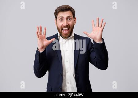 Überraschender Geschäftsmann mit Bart legt die Hände hoch und schreit Stockfoto