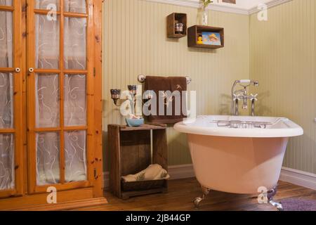 Freistehende Badewanne mit rollstuhlgerechter Oberseite und antike Möbel im Badezimmer im alten Backsteinhaus im kanadischen Cottage-Stil aus dem Jahr 1870. Stockfoto