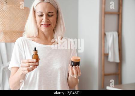 Morgen der reifen Frau mit kosmetischem Serum und Creme zu Hause Stockfoto