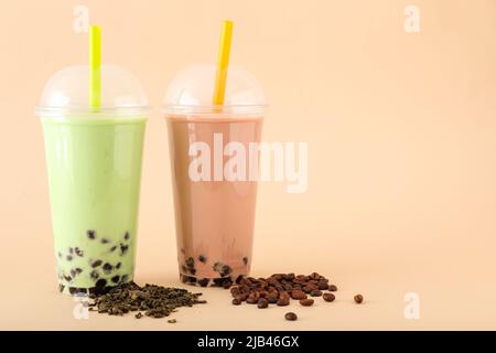 Plastikbecher mit verschiedenen leckeren Bubble Tea auf beigem Hintergrund Stockfoto