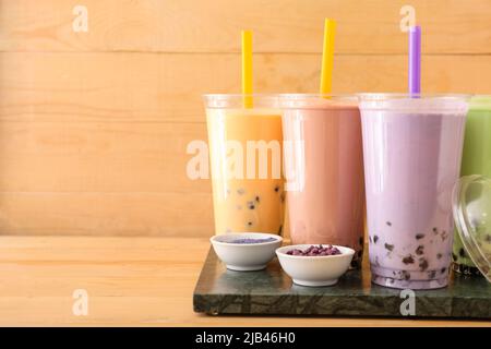 Tafel mit Plastikbechern mit verschiedenen leckeren Bubble Tea auf dem Tisch Stockfoto
