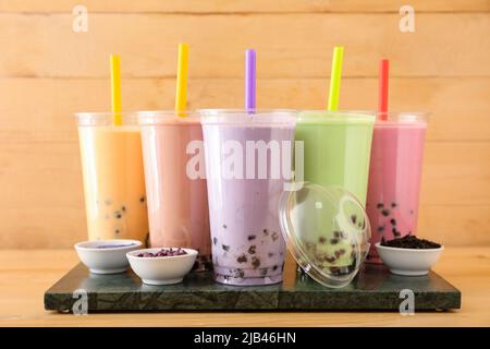 Tafel mit Plastikbechern mit verschiedenen leckeren Bubble Tea auf dem Tisch Stockfoto