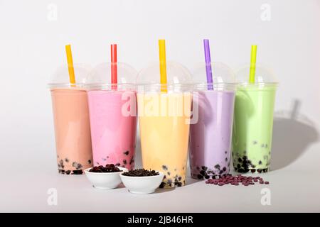 Plastikbecher mit verschiedenen leckeren Bubble Tea auf hellem Hintergrund Stockfoto
