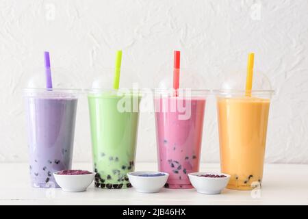 Plastikbecher mit verschiedenen leckeren Bubble Tea auf dem Tisch Stockfoto