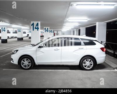 Moskau. Russland. 15. September 2021. Seitenansicht eines weißen Autos Lada Vesta SW, in der Kombi-Karosserie. Modernes russisches Auto Lada Vesta SW auf einem leeren Parkplatz in der Nacht. Stockfoto