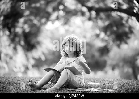 Kindererziehung im Freien. Ein kleiner Junge Schülerin genießt ihr Lernen im Park. Stockfoto