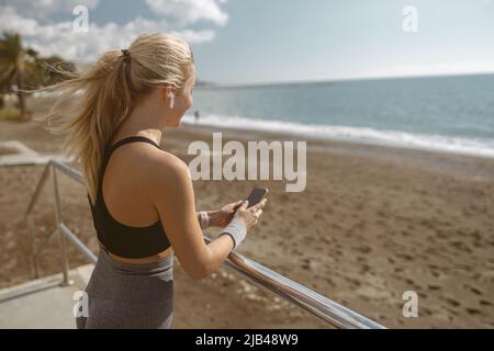 Model beim Musikhören während des Trainings in Meeresnähe Stockfoto