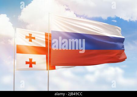 Sonniger blauer Himmel und Flaggen von russland und georgien Stockfoto