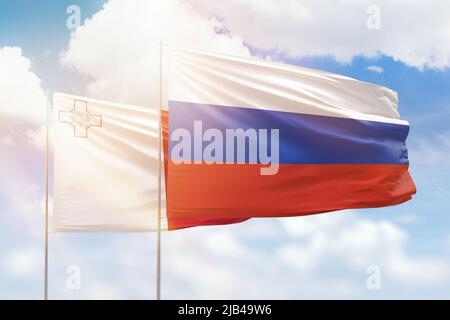 Sonniger blauer Himmel und Flaggen von russland und malta Stockfoto