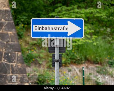 Einwegschild in deutscher Sprache 'Einbahnstraße'. Der weiße Pfeil zeigt die Verkehrsrichtung an. Verkehrsteilnehmer müssen die Informationen befolgen. Stockfoto