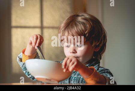 Kinder essen. Kleiner Junge beim Frühstück in der Küche. Nettes Kind, das zu Hause frühstücken kann. Babynahrung. Stockfoto