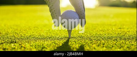 Nahaufnahme eines Golfspielers, der mit Handschuhen den Golfball auf einem Abschlag auf dem Golfplatz platziert Stockfoto