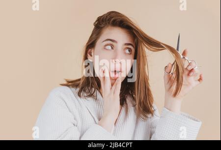 Traurige Frau, die ihre Haare mit einer Schere schneiden ließ. Schöne Frau in Panik wegen Haarausfall. Frau mit Haarausfall Problem. Stockfoto