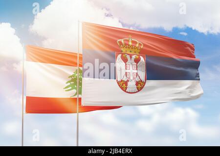 Sonniger blauer Himmel und Flaggen von serbien und libanon Stockfoto