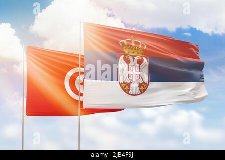Sonniger blauer Himmel und Flaggen von serbien und tunesien Stockfoto