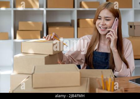 Drop Versand Geschäft Eigentümer sprechen auf Handy und die Bestellung. Weibliche Unternehmerin arbeitet im Home Office Bestätigung der Bestellung am Telefon. Stockfoto