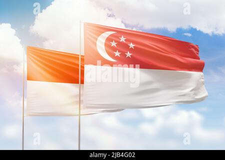 Sonniger blauer Himmel und Flaggen von singapur und indonesien Stockfoto
