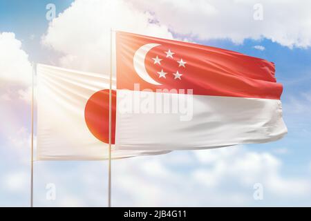 Sonniger blauer Himmel und Flaggen von singapur und japan Stockfoto