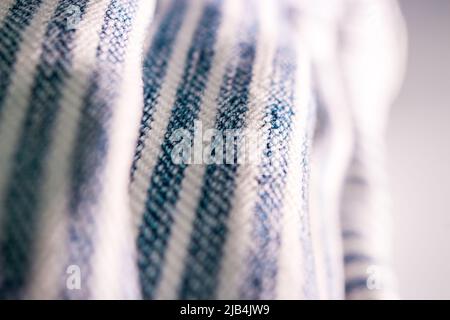 Die Nahaufnahme von faltbaren Overalls mit blauem Streifenmuster im Sonnenlicht. Stockfoto