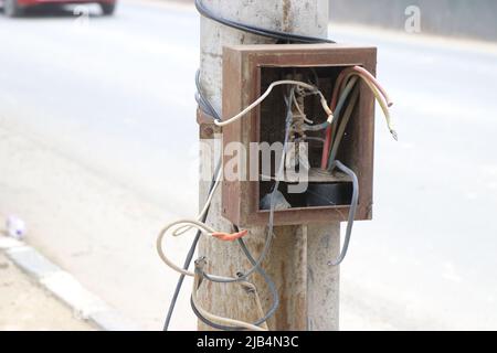 Elektrischer Sicherungskasten mit gebrochenen Kabeln oder verlassene Schaltkasten an einer Straßenbeleuchtung Stockfoto