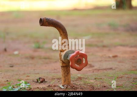 Wasserregelventil alt und rostig, das verwendet wird, um den Schlauch zu verbinden und die Gartenpflanzen im Boden in einem Garten zu bewässern Stockfoto