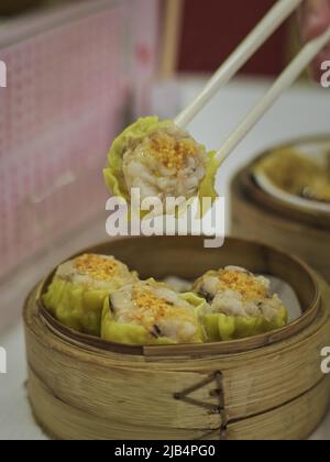 Köstliches chinesisches Dim Sum in einem chinesischen Restaurant, Essstäbchen mit gedämpfter Reisrolle Stockfoto