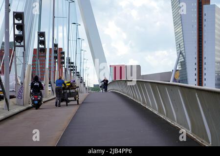 Fahrradfahrer und Motorrad überqueren am 27,2022. Mai die Erasmus-Brücke vom Wilhelminaplein in Rotterdam bei windigem Wetter; Niederlande. Stockfoto