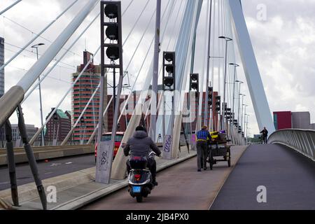 Fahrradfahrer und Motorrad überqueren am 27,2022. Mai die Erasmus-Brücke vom Wilhelminaplein in Rotterdam bei windigem Wetter; Niederlande. Stockfoto