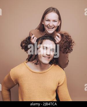 Lustige Zeit zusammen. Freudige Momente zu zweit. Fröhliche Mädchen halten lockiges Haar von Freund macht ihn lustig Frisuren. Stockfoto