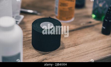 Rolle von schwarzem Nackenschutzband oder Papier, das vom Friseur und Friseur verwendet wird, um Hals und Körper vor herabfallenden Haaren zu schützen. Rolle stehend auf dem Tisch Stockfoto