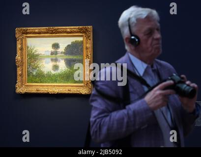 Potsdam, Deutschland. 02.. Juni 2022. Ein Mann steht im Museum Barberini neben dem Gemälde 'der Spulenbaum in Argenteuil' Öl auf Leinwand, 1876) von Claude Monet. Das Gemälde ist eines von vier kürzlich von Hasso Plattner erworbenen Gemälden. Quelle: Soeren Stache/dpa/Alamy Live News Stockfoto