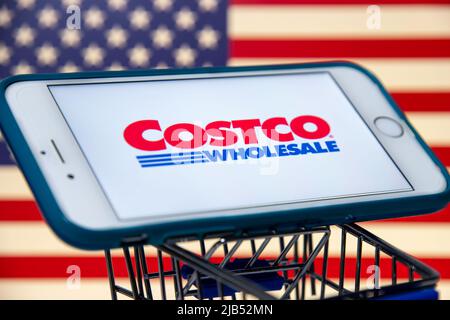 Logo von Costco, einem US-amerikanischen multinationalen Konzern, betreibt eine Kette von nur Mitgliedschaftsclubs auf dem iPhone im Warenkorb mit US-Flagge. Stockfoto