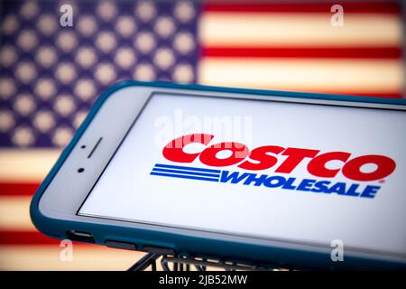 Logo von Costco, einem US-amerikanischen multinationalen Konzern, betreibt eine Kette von nur Mitgliedschaftsclubs auf dem iPhone im Warenkorb mit US-Flagge. Stockfoto