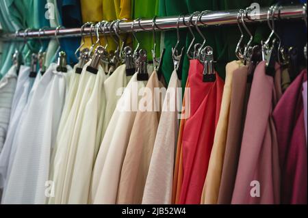 Muster von Stoffen in hellen Farben hängen an der Metallregal-Bar Stockfoto