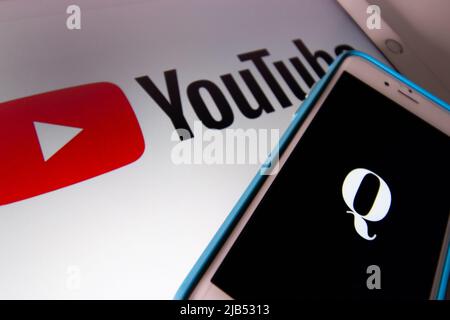 Kumamoto / JAPAN - Okt 20 2020 : das Logo von Qanon, einer rechtsextremen Verschwörungsgruppe, auf dem iPhone mit YouTube auf dem iPad Stockfoto