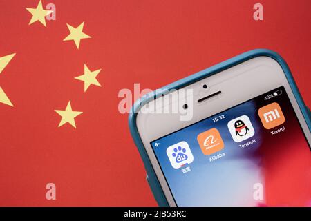 BATX China Big Tech (Baidu, Alibaba, Tencent & Xiaomi) auf iPhone auf chinesischer Flagge. BATX ist von GAFA (Google, Amazon, Facebook & Apple) konterreß Stockfoto