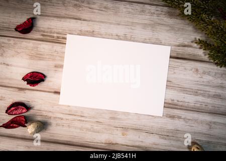 Femininer Desktop-Mockup mit leerer weißer Papierkarte, Ästen und Pot Pourri auf weißem schäbigen Tischhintergrund. Für Webbanner. Stylischer, flacher Lay Stockfoto
