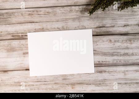 Feminines Desktop-Modell mit weißer, weißer Papierkarte und Zweigen auf weißem, schäbigen Tischhintergrund. Für Webbanner. Stylisches, flaches Lay-Design, Draufsicht Stockfoto