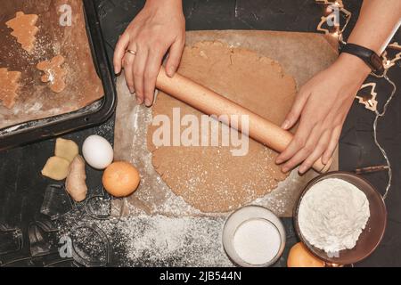 Lebkuchen mit einer Lebkuchenform aus dem Teig schneiden, Draufsicht, roher Teig mit Zimt zum Backen vorbereitet. Das Muster auf dem Teig der Feige Stockfoto